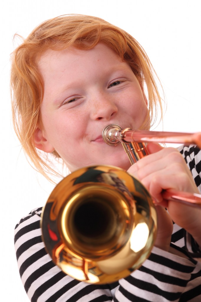 Young girl playing a trombone on white background